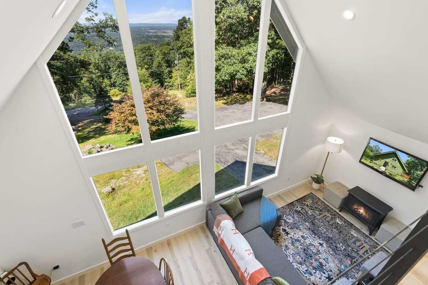 A high-ceiling room with large windows overlooking a lush landscape.