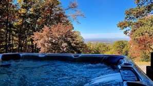 Un bain à remous avec vue sur une forêt et un paysage lointain.