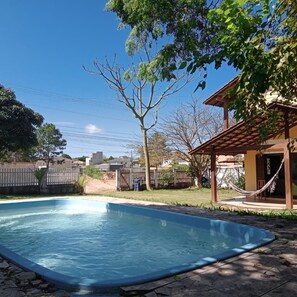 Piscina com deck de madeira e uma rede.