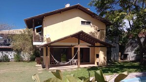 A two-story house with a balcony, a covered patio, and a swimming pool. - Comfortable house in Florianópolis |Moçambique Beach (Florianópolis)