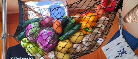 A kitchen area with a hanging net filled with vegetables.
