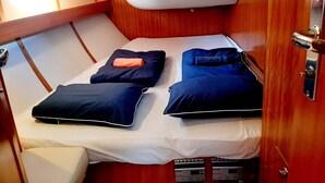 A compact cabin with a single bed, a small seating area, and a wooden interior. - Sailing between the Sporades Islands (Sciato)