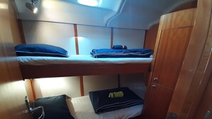 A bunk bed room with wooden bunk beds, a wardrobe, and a small table. - Sailing between the Sporades Islands (Sciato)
