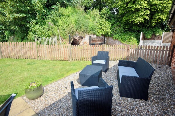 An outdoor patio with wicker furniture and a small garden area. - Dog and family friendly barn conversion with fully enclosed garden and hot tub (Dilham)