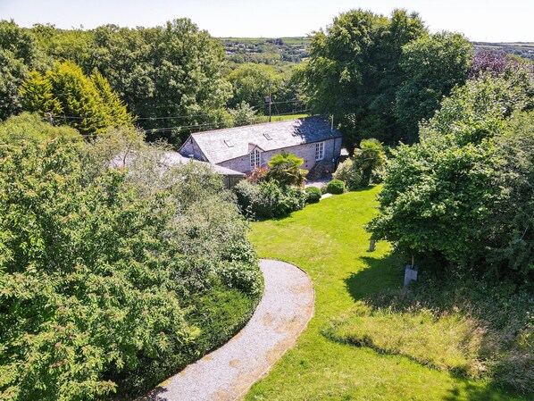 A rural house with a gravel driveway and a well-maintained lawn.