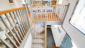 A staircase with striped carpet, white railings, and a wooden handrail. - Stone Barn is a stunning barn in an idyllic hamlet, sleeps 6, games room, + dogs (Lanteglos)