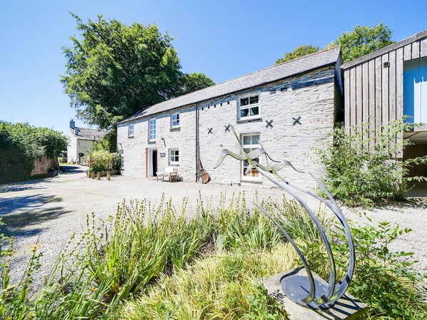 A stone building with a gravel driveway, a metal sculpture, and a large tree in the background. - Stunning barn in an idyllic hamlet, sleeps 6 + dogs (Lanteglos)