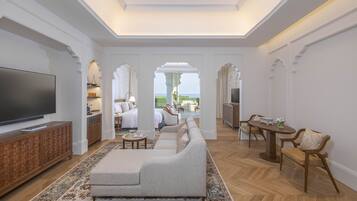 Amplia sala de estar con un televisor de pantalla plana grande, un sofá, un comedor con sillas y vistas al exterior.