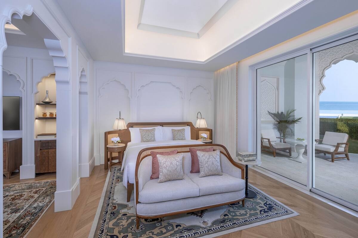 Un dormitorio con una cama grande, un sofá y vista al mar a través de una puerta de cristal.