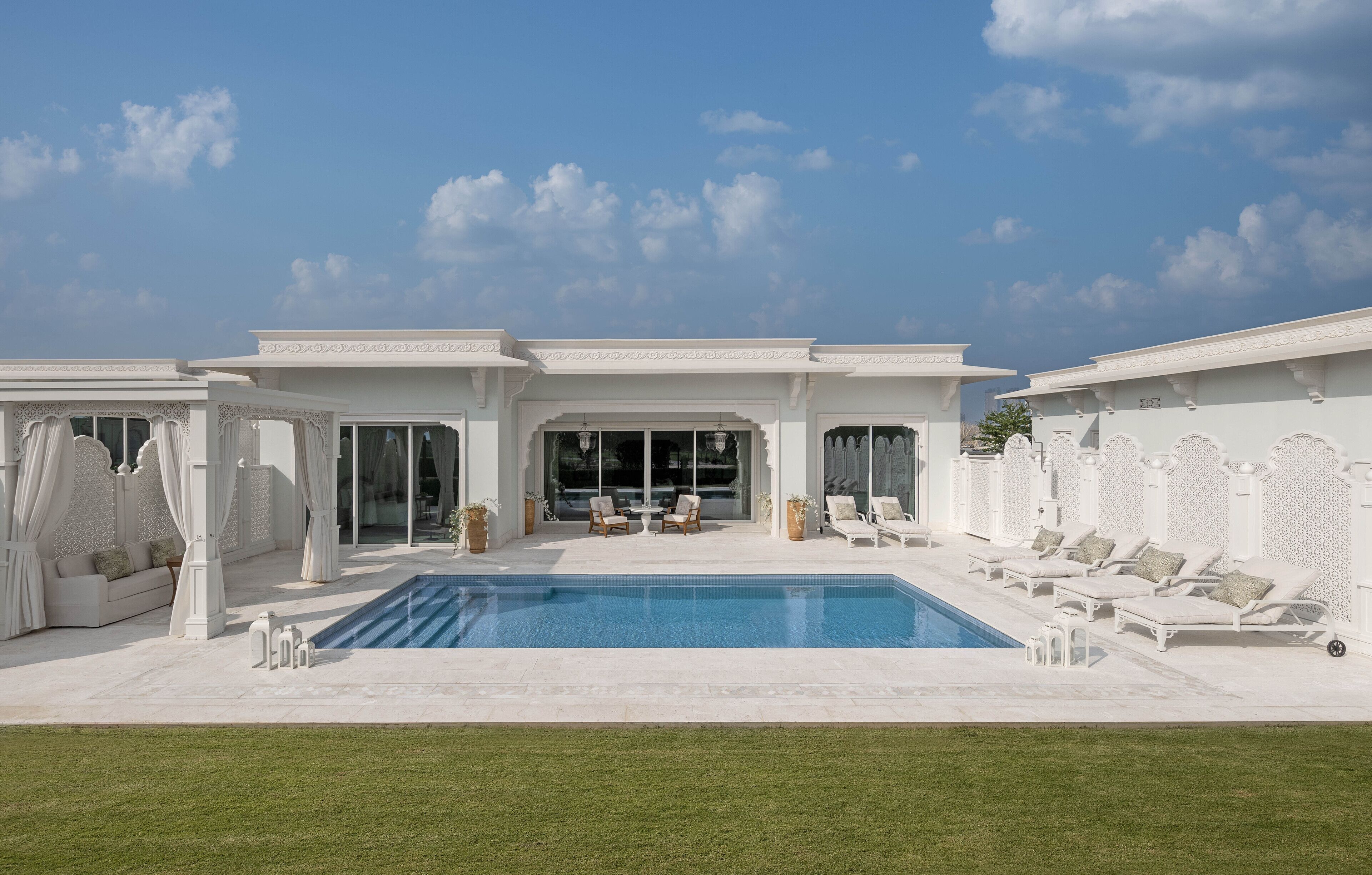 A poolside area with a pool, lounge chairs, and a seating area with a table and chairs.