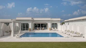 A poolside area with a pool, lounge chairs, and a seating area with a table and chairs.