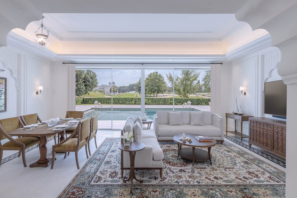 Un salón amplio con vistas a la piscina, muebles elegantes y un televisor grande.