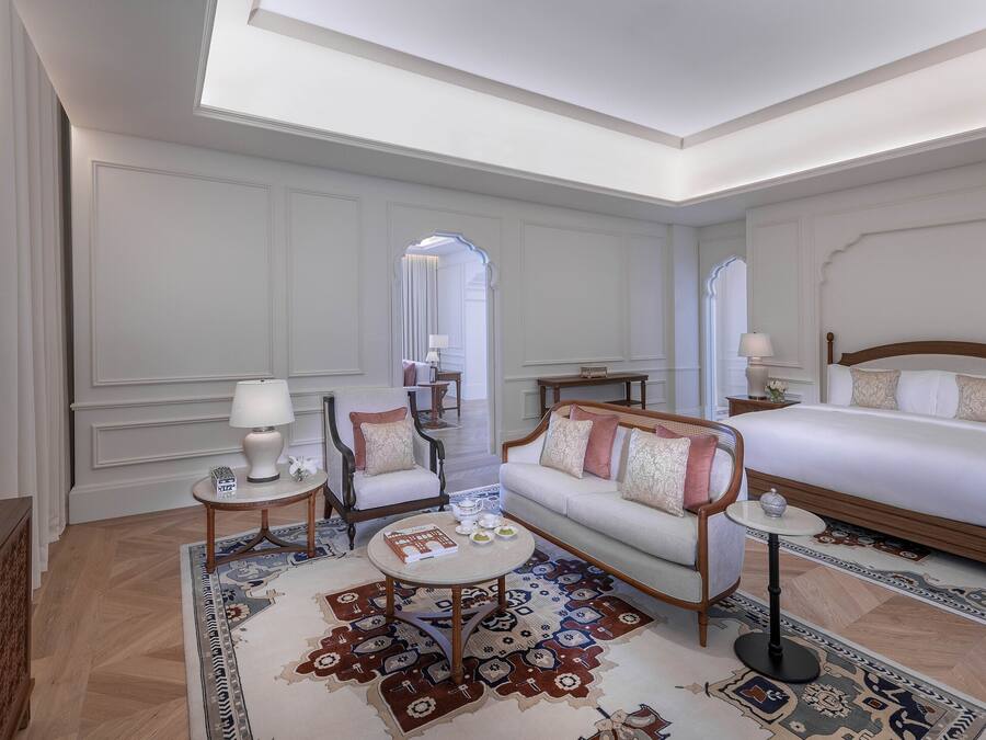 A hotel room with a bed, sofa, TV, lamp, and decorative rugs.