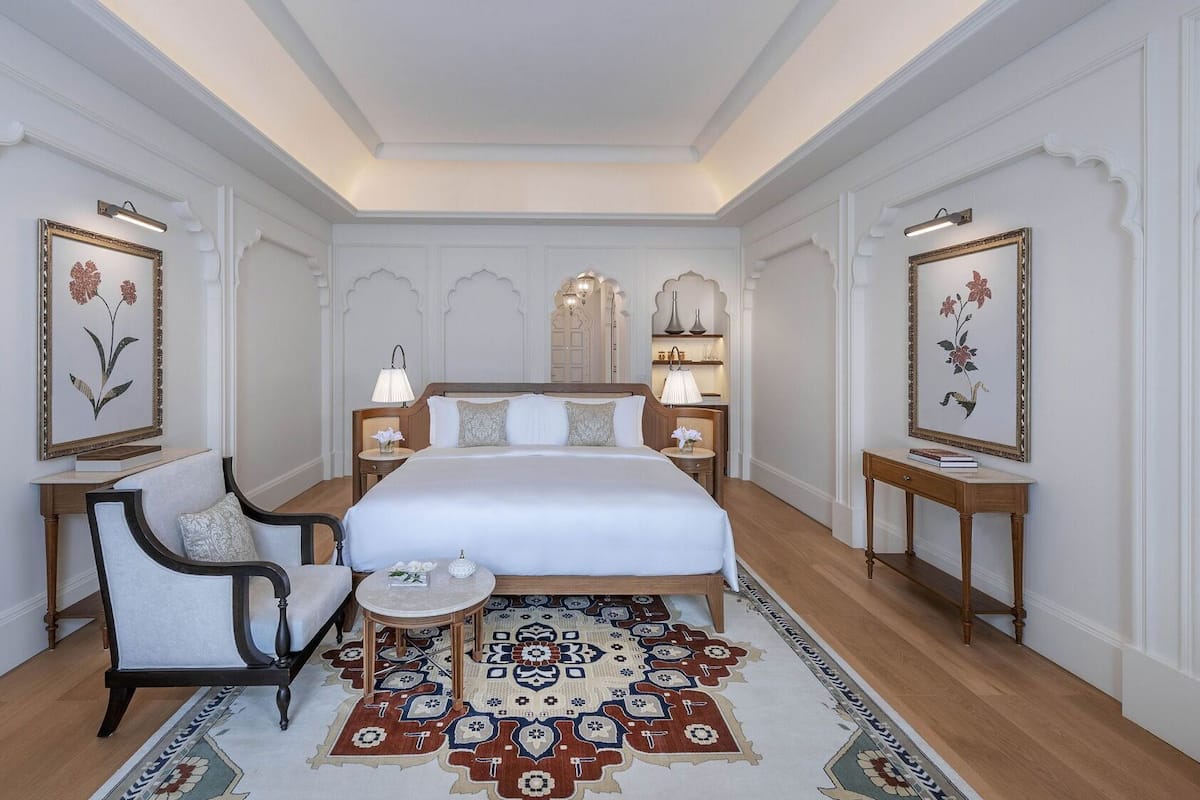 Una habitación de hotel con una cama grande, una silla, una mesita y dos mesitas de noche.