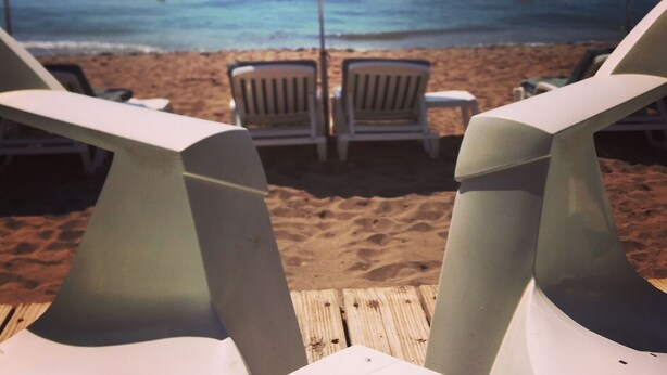 Une plage avec des parasols jaunes et des chaises longues blanches.