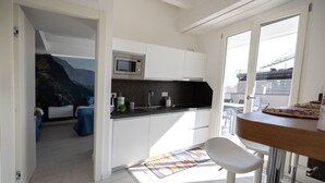 Cozinha moderna com armários brancos, micro-ondas e um espaço bar com pizza.