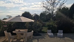An outdoor patio with a round table and chairs, a large umbrella, and two lounge chairs. - L'Antidote, estate with heated indoor pool 1h30 from Paris (Coulours)