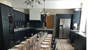 A long dining table set with plates and glasses, surrounded by dark cabinets and a tiled floor. - L'Antidote, estate with heated indoor pool 1h30 from Paris (Coulours)