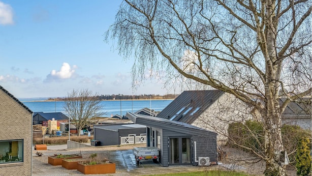 Una casa moderna con garaje, un pequeño jardín y vista al mar.