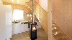 Una cocina moderna con armarios blancos, estufa de acero inoxidable y una escalera de madera.