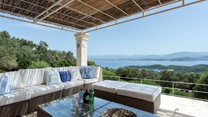 A covered outdoor seating area with a view of the sea and mountains. - Thea Lofou House (Corfu)