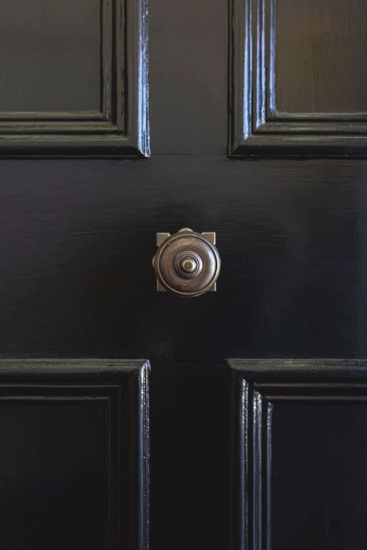 Una puerta de madera oscura con un pomo redondo en el centro.