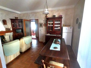A kitchen with a wooden dining table, a sofa, and a refrigerator.