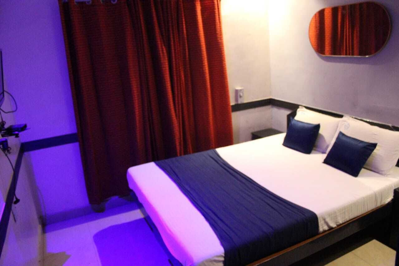 A hotel room with a bed, red curtains, a mirror, and a blue and white color scheme.