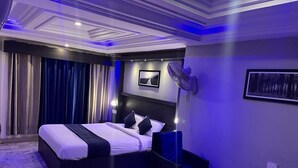 A bedroom with a bed, a desk, a chair, a fan, and a picture on the wall. - Sivabhagya SKR Madurai (Madurai)