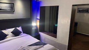 A hotel room with a bed, a nightstand, a mirror, and a window. - Sivabhagya SKR Madurai (Madurai)
