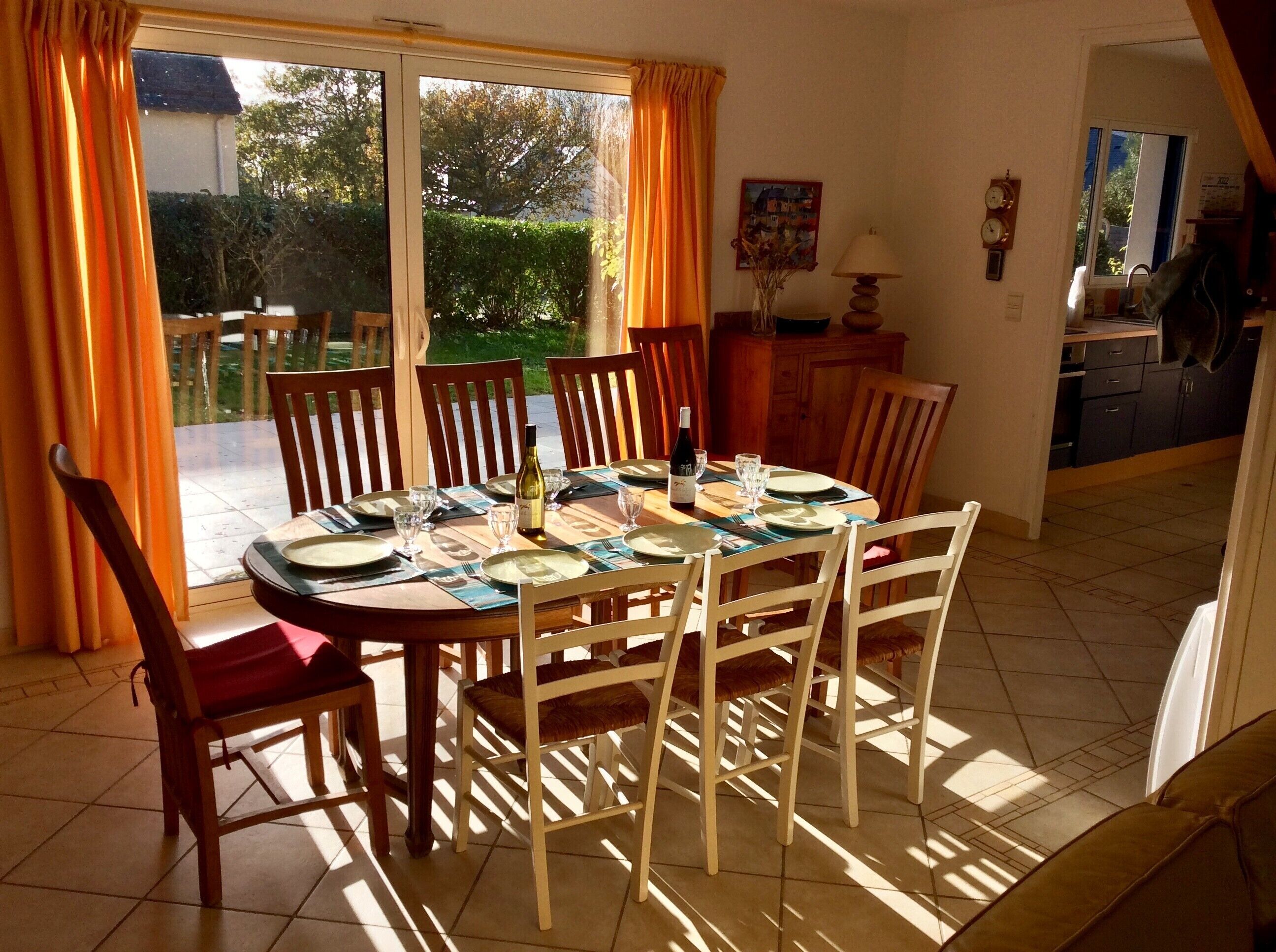 Un coin repas avec une table dressée pour quatre personnes, entourée de chaises en bois.