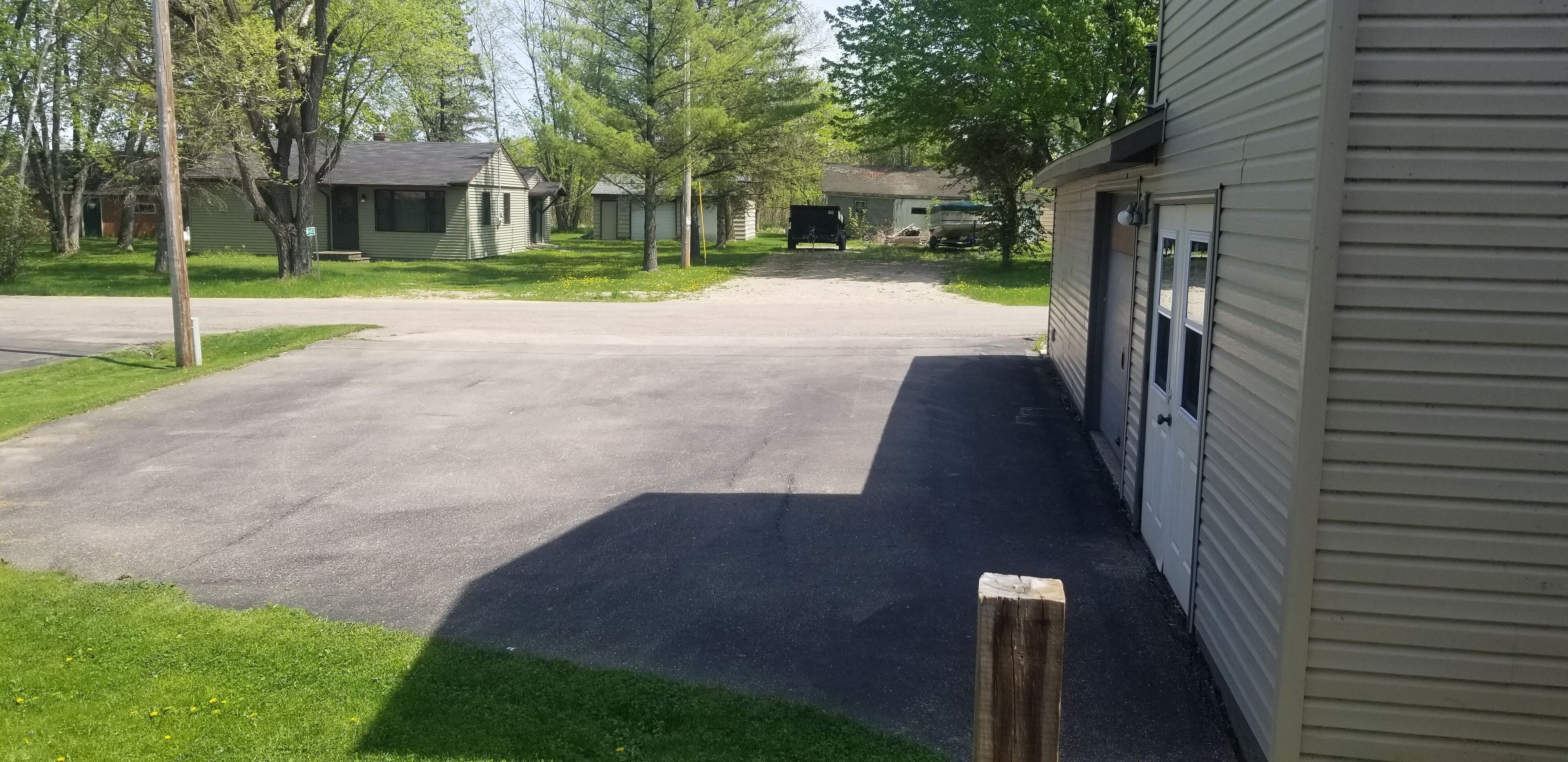 A residential driveway leading to a garage with a detached house in the background.
