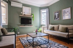 A living room with a sofa, a coffee table, a TV, and a patterned rug.