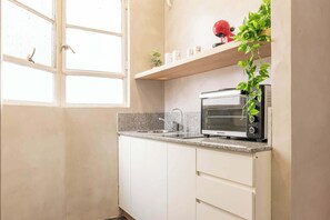 Eine Küche mit eingebautem Toaster, einem Fenster und einer Pflanze auf der Arbeitsplatte.