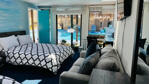 Ein modernes Hotelzimmer mit einem großen Bett, einer Couch und Blick auf einen Swimmingpool.