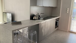 A modern kitchen with a large island, stainless steel appliances, and a flat-screen TV. - Apartment in detached house (Colmar)