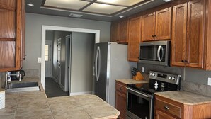 A modern kitchen with wooden cabinets, stainless steel appliances, and a large island. - Near Hospital & Shopping Centers- 3/2 with pool (Lafayette)