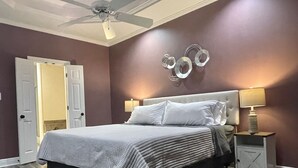 A bedroom with a bed, two bedside tables, a ceiling fan, and a door. - Near Hospital & Shopping Centers- 3/2 with pool (Lafayette)