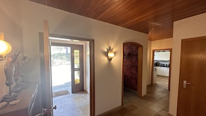 A hallway with a wooden ceiling, a stone-tiled floor, and a view into a kitchen area. - Villa close to Winterberg and Willingen (Bruchhausen)