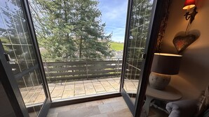 A room with a large glass door leading to a balcony with a view of trees and a fence. - Villa close to Winterberg and Willingen (Bruchhausen)