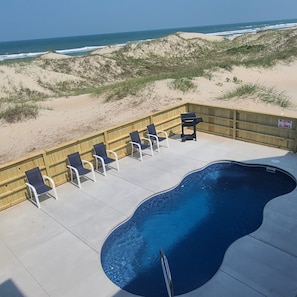 Zona de piscina con sillas de descanso y un letrero que indica que está prohibido bucear.