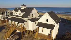 Ein Strandhaus mit mehreren Etagen, Holzterrassen und Blick auf den Ozean.