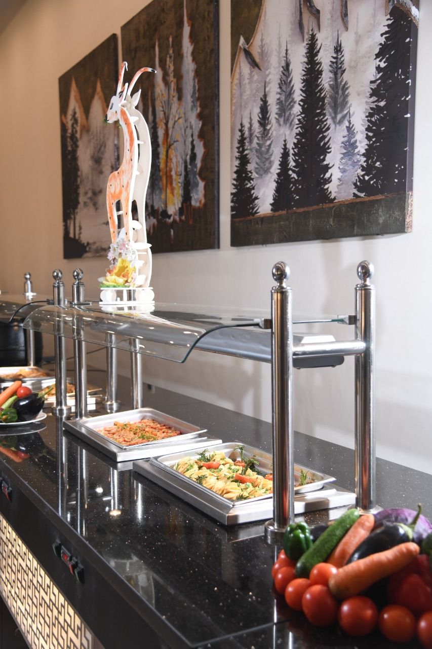 A buffet setup with various food items and a decorative animal sculpture.