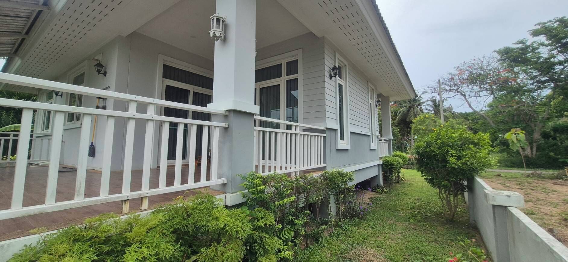 A two-story house with a covered porch and a small garden area.