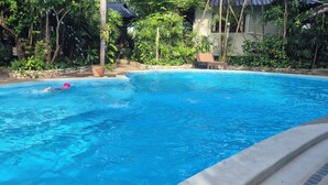 A swimming pool surrounded by lush greenery and a stone wall. - Resort house - 2 min walk to the beach (Amphoe Bang Saphan)