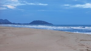 A beach with footprints leading to the water, a mountain in the background, and a clear sky. - Resort house - 2 min walk to the beach (Amphoe Bang Saphan)