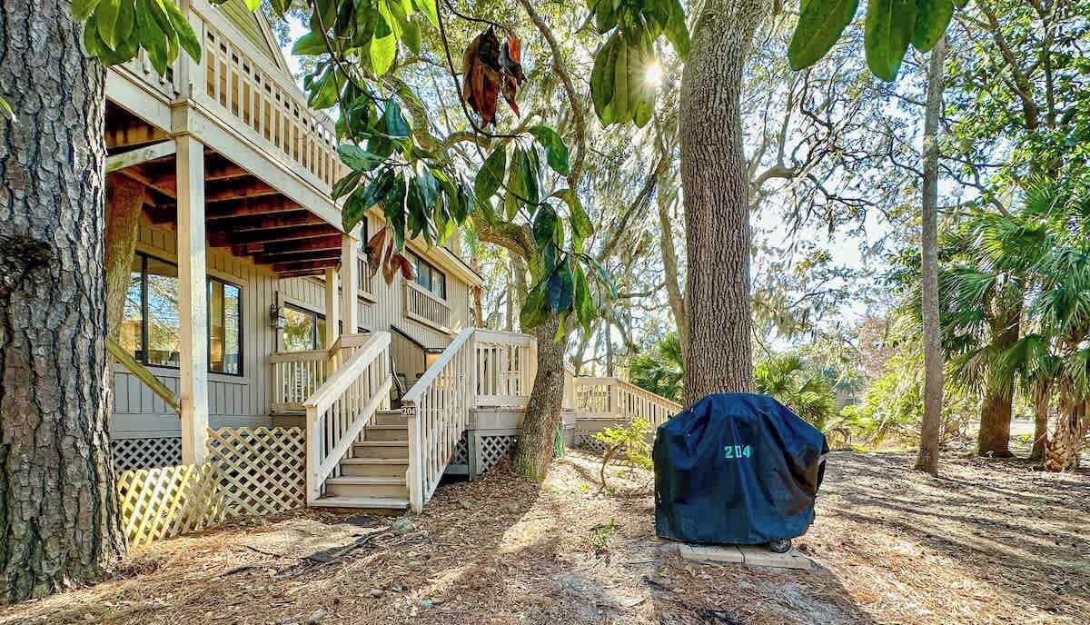 Une terrasse en bois avec un escalier menant à un balcon, le tout entouré d’arbres.