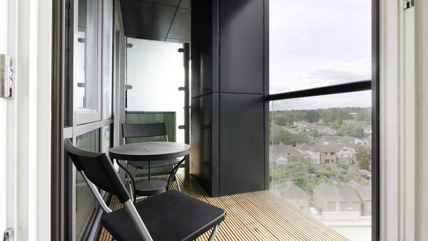 A balcony with a table and chairs, a view of a residential area, and a large window. - KD Tower Abodebed (Hemel Hempstead)
