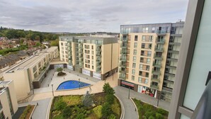 A modern apartment complex with multiple floors, balconies, and a central courtyard with a blue pool. - KD Tower Abodebed (Hemel Hempstead)
