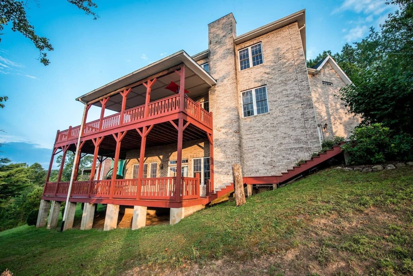 Ein zweistöckiges Steinhaus mit einem roten Balkon und einem Steinsschornstein.